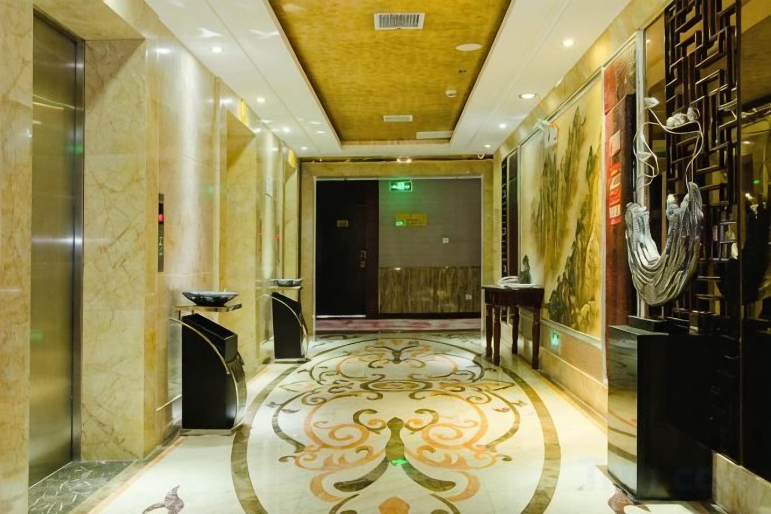 Un vestíbulo de hotel con piso de mármol, una recepción y una escultura en la pared.