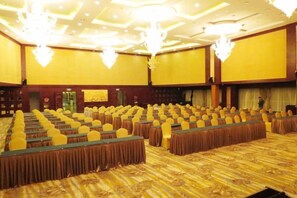 A conference room with rows of tables and chairs, a patterned carpet, and chandeliers. - Jiu Long International Hotel (Mengcheng)