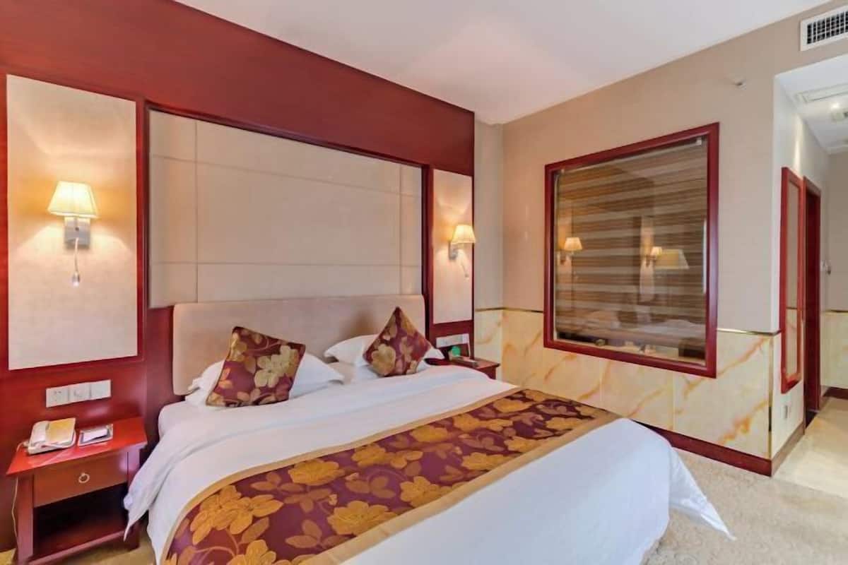 A hotel room with a large bed, bedside lamps, a nightstand, and a mirror.
