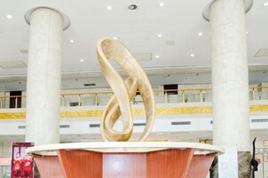 Un interior moderno con una pieza escultórica central, columnas grandes y un techo alto.