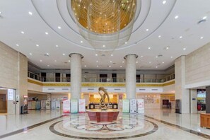 A spacious lobby with a central decorative fountain, multiple levels of balconies, and a modern ceiling design.
