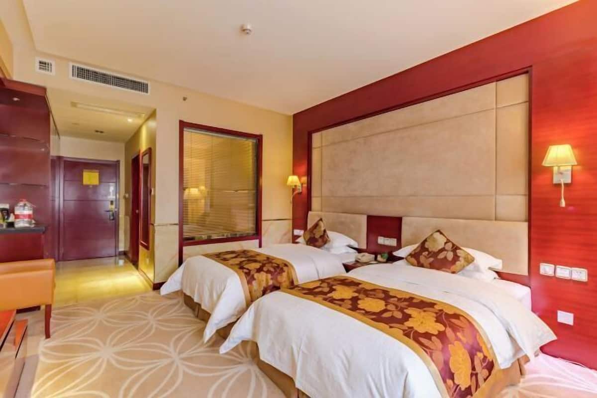 A hotel room with two beds, a desk, and a chair.