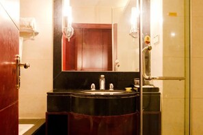 A bathroom with a black sink, a mirror, and a glass shower enclosure.