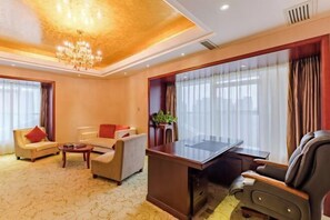 A hotel room with a large desk, two sofas, a coffee table, and a chandelier. - Jiu Long International Hotel (Mengcheng)