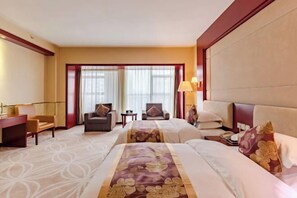 A hotel room with two beds, a desk, a chair, a lamp, and a view of the outside through large windows. - Jiu Long International Hotel (Mengcheng)