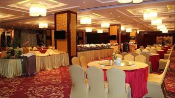 Un salón de banquetes con mesas redondas, sillas y un escenario.
