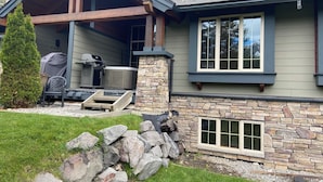 A house with a stone foundation, a covered patio with a grill, and a stone wall. - 3 BR Luxury Townhouse / Mountain views (Fernie)