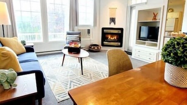 A living room with a sofa, a coffee table, a fireplace, and a television.