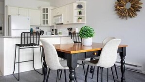 A dining area with a wooden table, four chairs, and a potted plant.