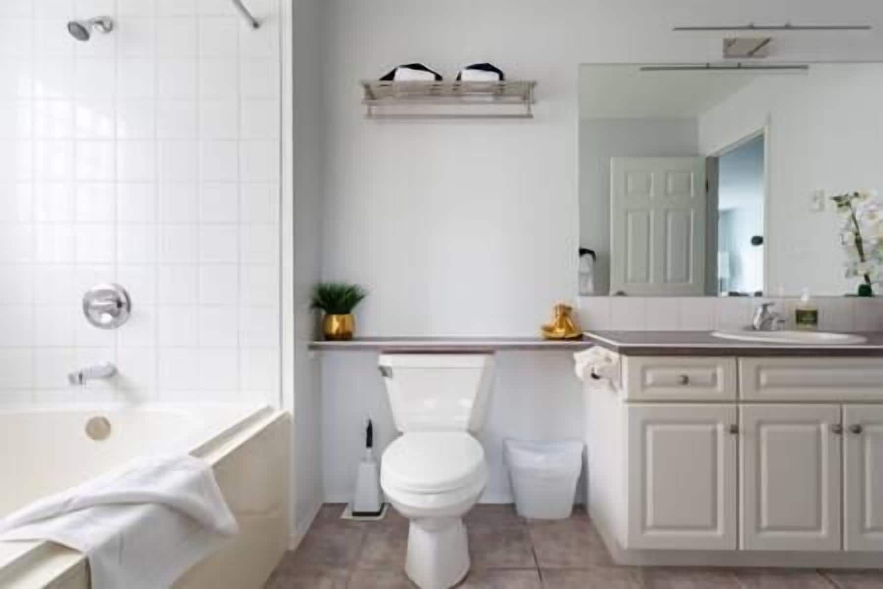 A bathroom with a bathtub, toilet, sink, and a mirror above the sink.