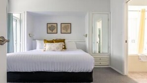 A bedroom with a bed, two wall-mounted pictures, a window, and a door.