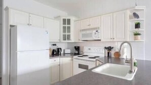 A modern kitchen with white cabinets, a built-in microwave, a stove, and a sink.