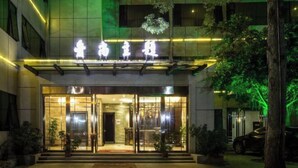 A hotel entrance with a modern design, featuring a glass facade and illuminated signage.