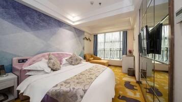 Een hotelkamer met een bed, een stoel, een televisie en een grote spiegel.