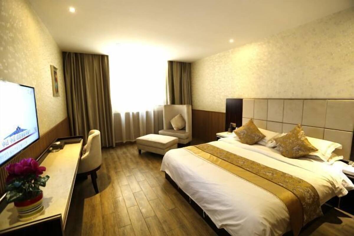 Une chambre d’hôtel équipée d’un lit, d’un bureau, d’une chaise, d’une télévision et d’une fenêtre avec des rideaux.