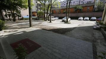A parking area with several cars, trees, and a building in the background.