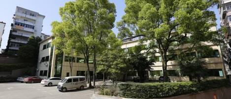 Ein Parkplatz mit Autos, ein mehrstöckiges Gebäude und Bäume.