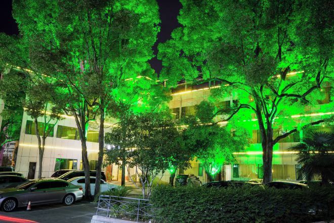 A building with a modern design, surrounded by trees and parked cars.