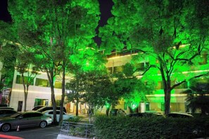 Un edificio de diseño moderno, rodeado de árboles y coches estacionados.