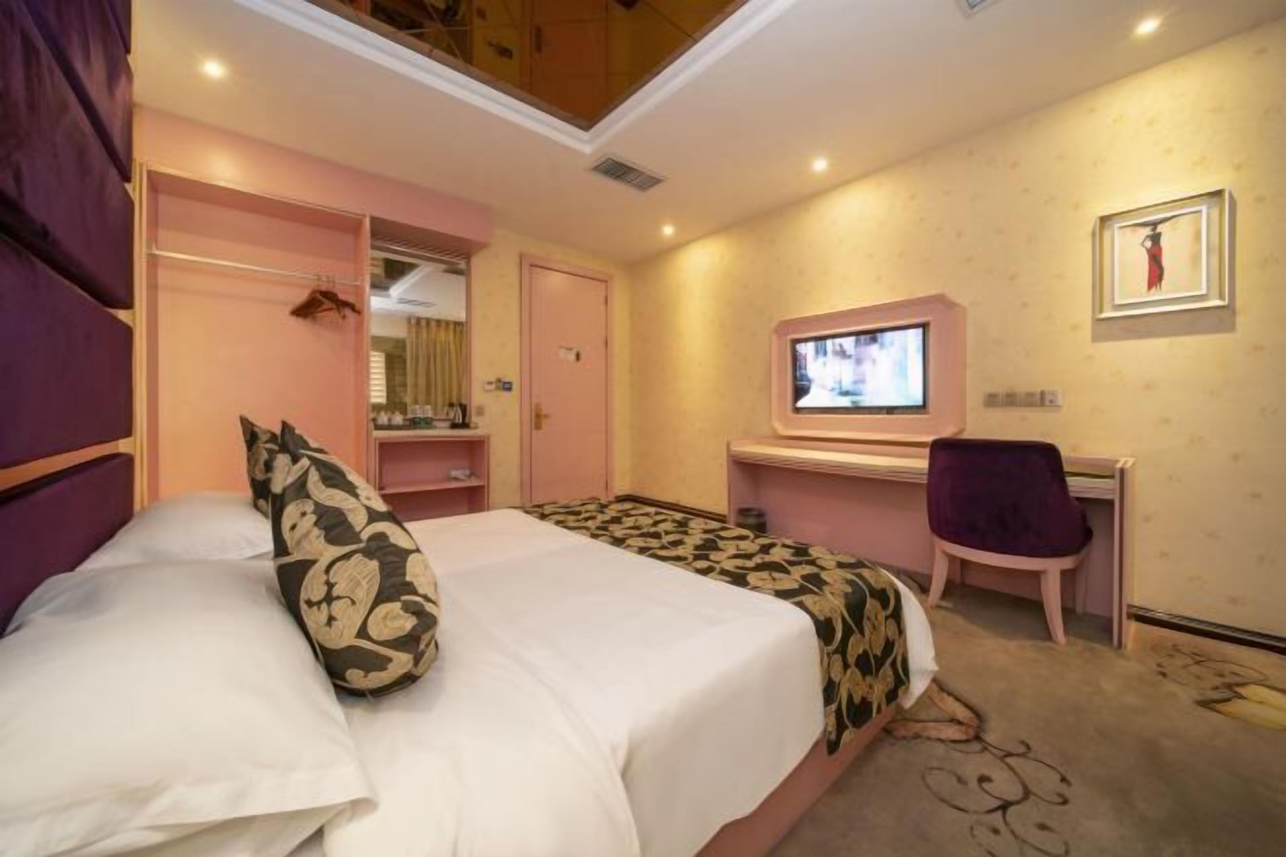 Une chambre d’hôtel comprenant un lit, un bureau, une chaise, une télévision et une armoire.