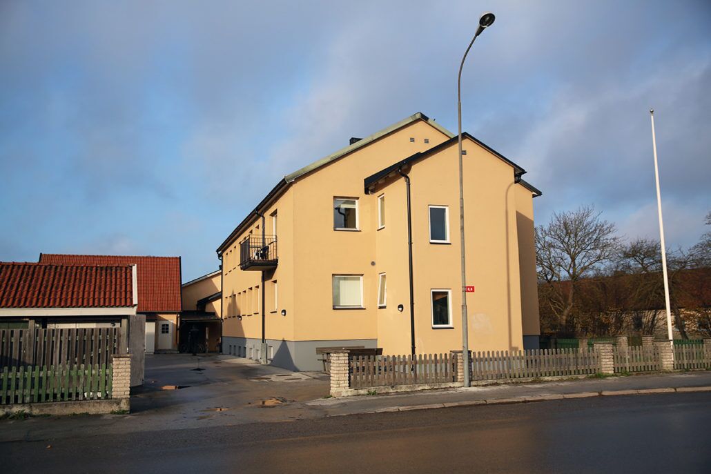 A two-story building with a flat roof, a balcony on the second floor, and a streetlight in front.