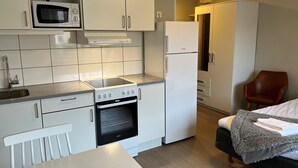 Una cocina pequeña con armarios blancos, microondas, estufa y refrigerador.
