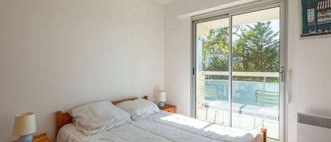A bedroom with a bed, a nightstand, a lamp, and a sliding glass door leading to an outdoor area.