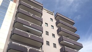 Un immeuble à plusieurs étages doté de balcons, d’un appareil de climatisation visible et d’un lampadaire.