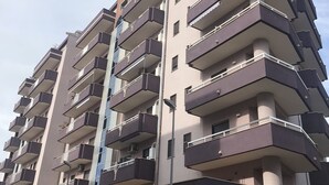 Un immeuble résidentiel à plusieurs étages, doté de balcons, d’un escalier central et d’un toit plat.