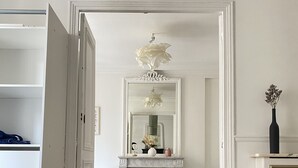Een slaapkamer met een bed, een witte kast, een open haard en een spiegel.