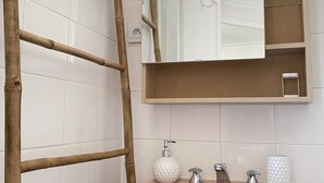 Een badkamer met een roze wastafel, een houten trap, een spiegel en een zeepdispenser.