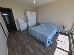 A bedroom with a bed, a wardrobe, a dresser, a nightstand, and a lamp.