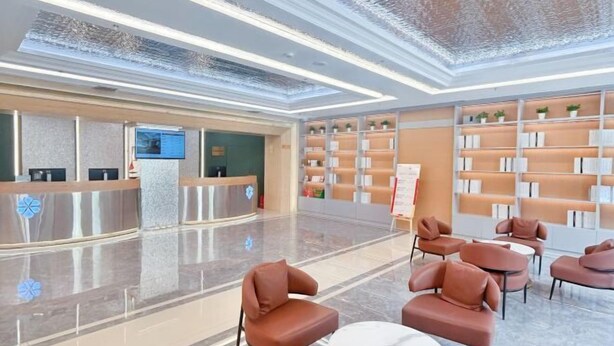 A modern lobby with a reception desk, seating area, and shelves with books. - Jinjiang Business Hotel (Yilan)