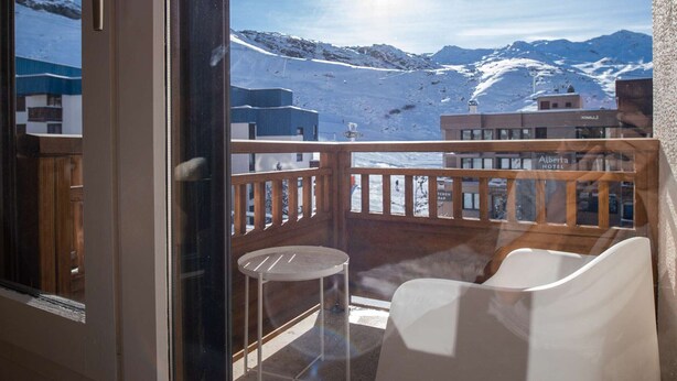 Ein Balkon mit Blick auf schneebedeckte Berge und ein Gebäude mit der Aufschrift 'Alberta Hotel'.
