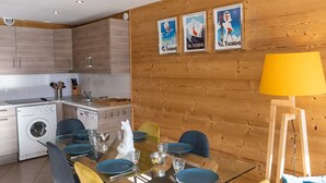 Eine moderne Küche mit Holzausstattung, einer Waschmaschine und einem Essbereich mit Glastisch und Stühlen.