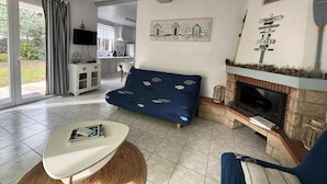 Een woonkamer met een blauwe bank, een witte salontafel en een open haard.