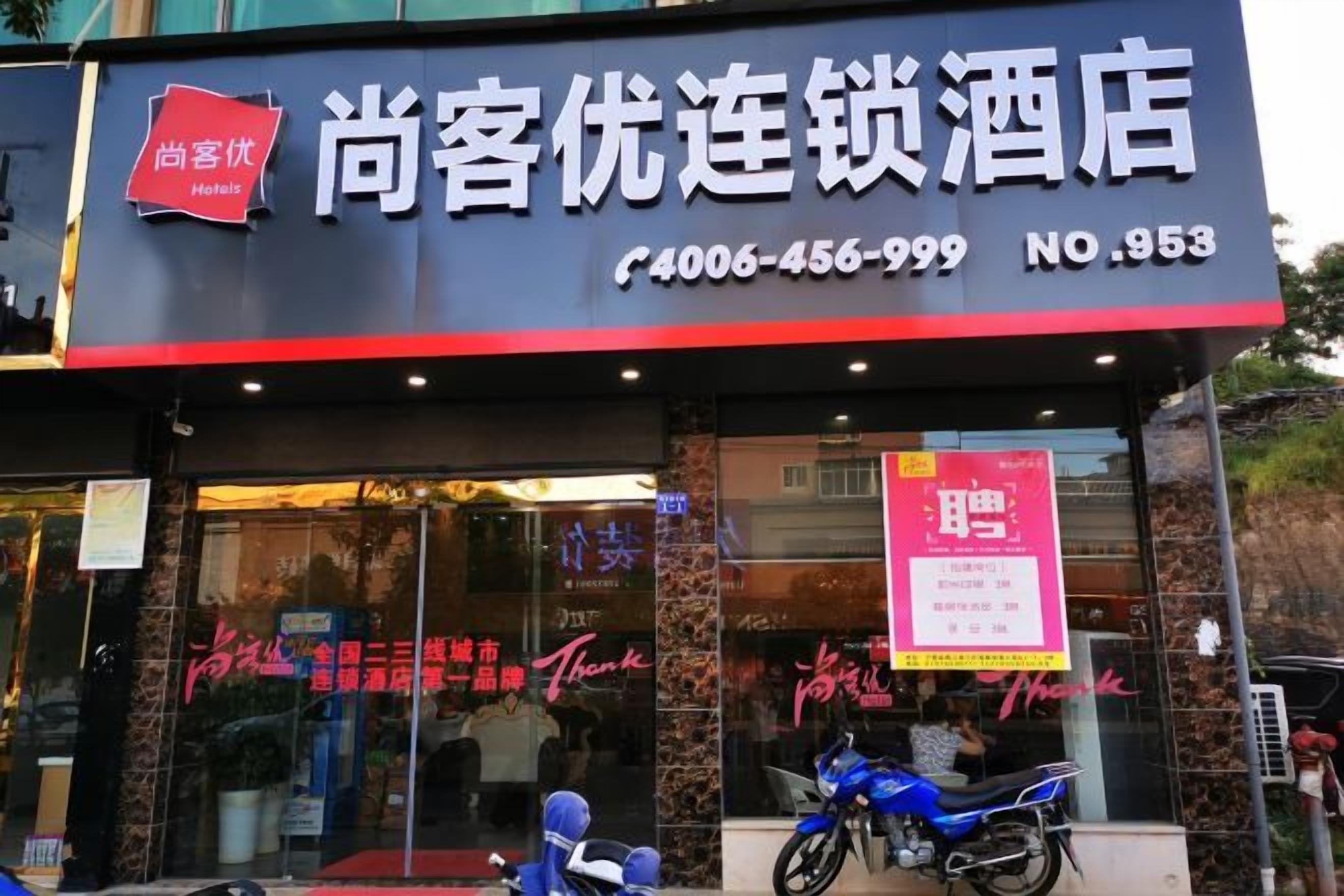 A hotel with a signboard displaying the name and contact information.