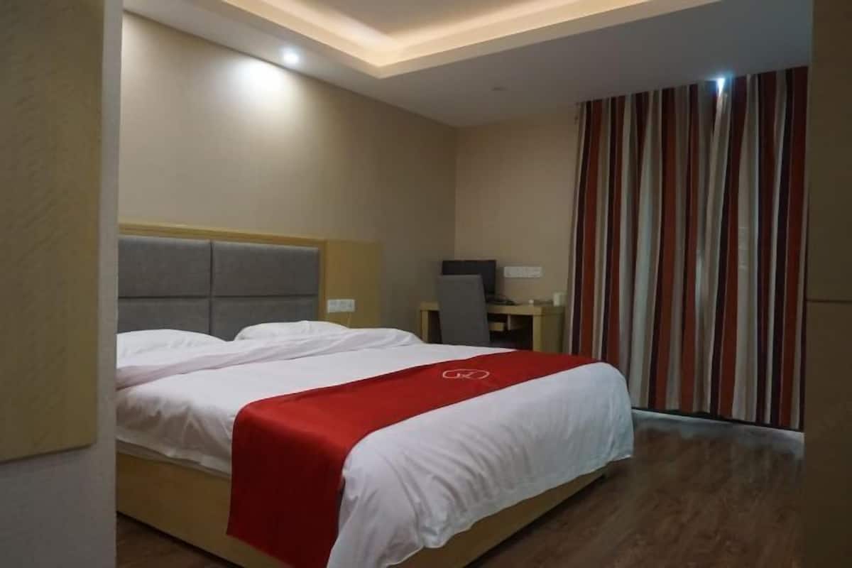 A hotel room with a bed, a desk, and a television.