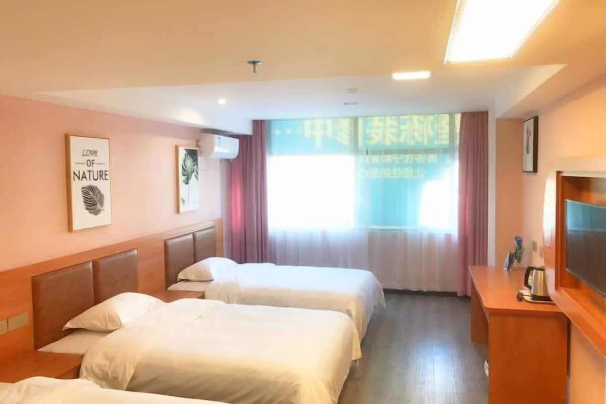 A hotel room with two beds, a desk, and a TV.
