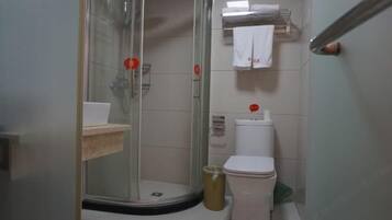 A bathroom with a glass shower enclosure, a toilet, a sink, and a towel rack.