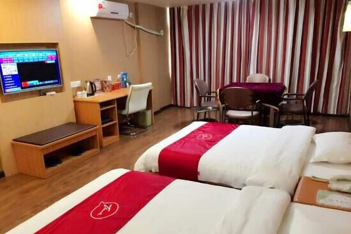 A hotel room with a bed, desk, chair, TV, and curtains.