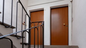 Escada com corrimãos de metal que leva a um conjunto de portas de madeira.