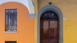 Um edifício com porta marrom, entrada em arco e janela com grades de metal elaboradas.