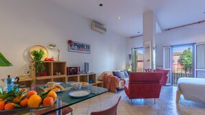 Uma sala de estar moderna com uma mesa de jantar de vidro, cadeiras vermelhas, um sofá e uma cama.
