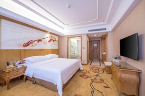 A hotel room with a bed, bedside table, TV, and a floral carpet. - Vienna International Hotel (Yushan Sanqing Square) (Yushan)
