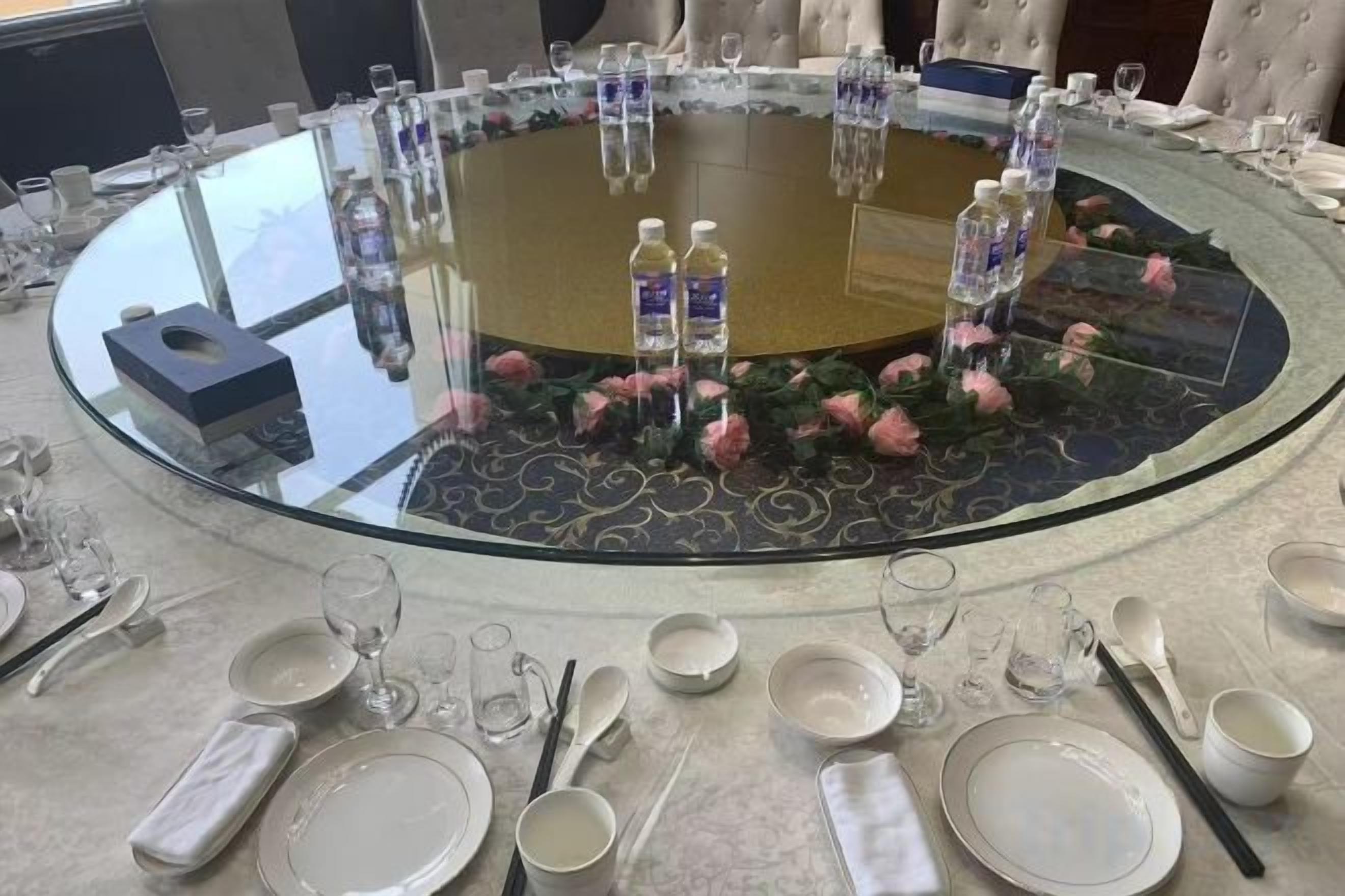 A round table set for a meal with water bottles, glasses, and cutlery.