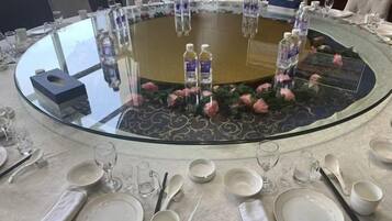A round table set for a meal with water bottles, glasses, and cutlery.