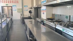 Une cuisine professionnelle dotée de plans de travail en acier inoxydable, d’équipements de cuisson et de divers ustensiles.