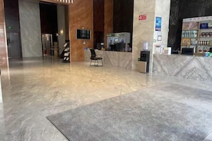 Un hall d’hôtel comprenant un comptoir d’accueil, un espace salon et un distributeur automatique.