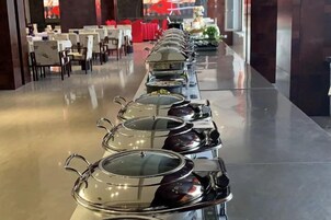 Una larga mesa de buffet con utensilios para servir alimentos cubiertos.